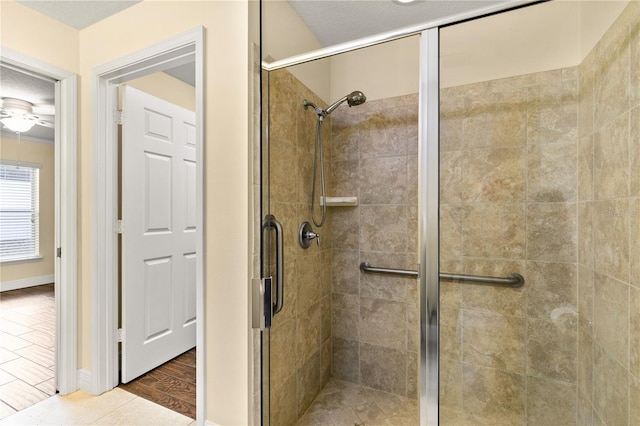 bathroom with hardwood / wood-style floors, ceiling fan, and an enclosed shower