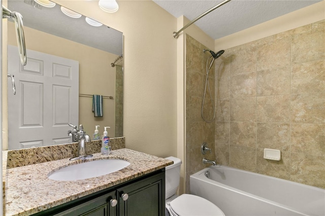 full bathroom featuring vanity, a textured ceiling, tiled shower / bath combo, and toilet