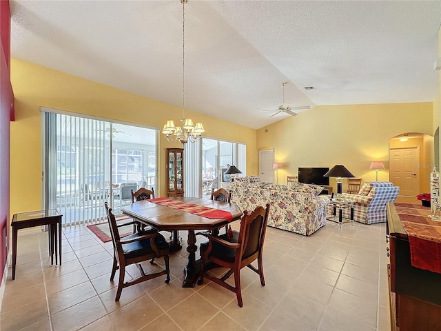 tiled dining area with a textured ceiling, ceiling fan with notable chandelier, and lofted ceiling