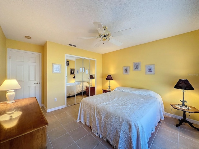 tiled bedroom featuring ceiling fan, a textured ceiling, and a closet