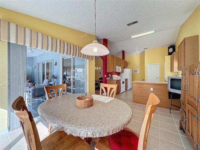 dining area with a textured ceiling, vaulted ceiling, and light tile patterned flooring