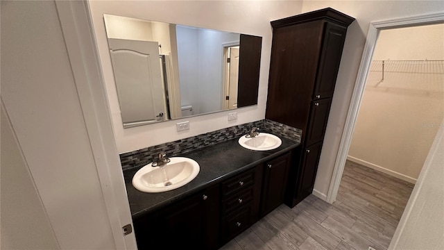 bathroom with hardwood / wood-style flooring, vanity, toilet, and tasteful backsplash