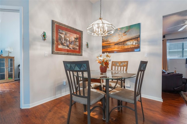 dining space with ceiling fan with notable chandelier and dark hardwood / wood-style flooring