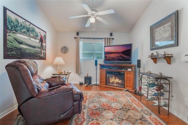 living room featuring ceiling fan, wood-type flooring, lofted ceiling, and a textured ceiling