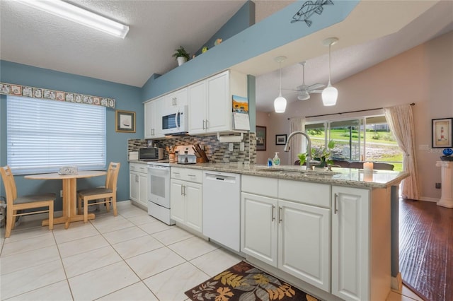 kitchen featuring lofted ceiling, white cabinetry, white appliances, and sink