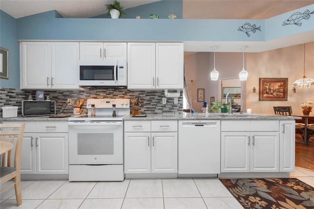 4130 Capland Ave, Clermont, FL 34711 - kitchen featuring white appliances, a sink, a peninsula, light tile patterned floors, and white cabinetry