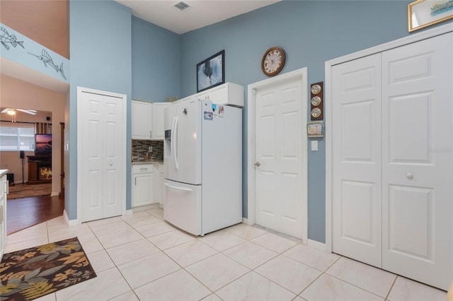 4130 Capland Ave, Clermont, FL 34711 - kitchen featuring white refrigerator with ice dispenser, white cabinets, light tile patterned floors, backsplash, and a high ceiling