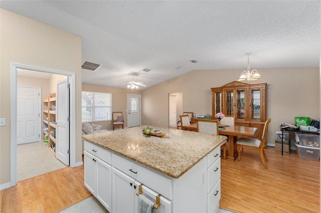 kitchen featuring decorative light fixtures, white cabinetry, a kitchen island, and light hardwood / wood-style floors