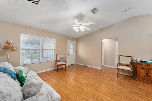 sitting room with a textured ceiling, light hardwood / wood-style floors, ceiling fan, and lofted ceiling