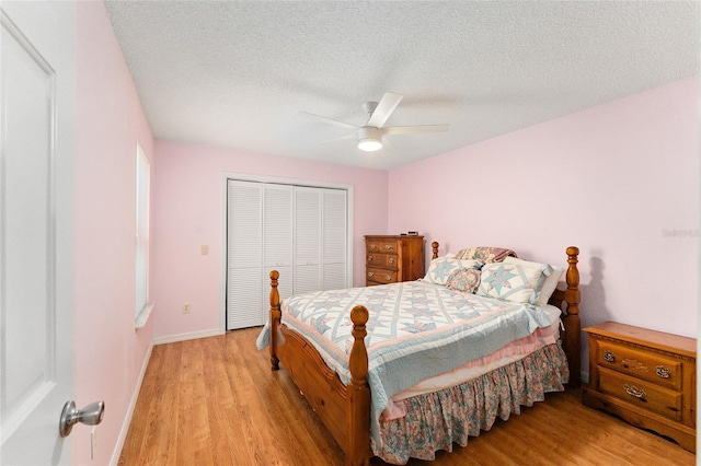 bedroom with ceiling fan, light wood-type flooring, a textured ceiling, and a closet