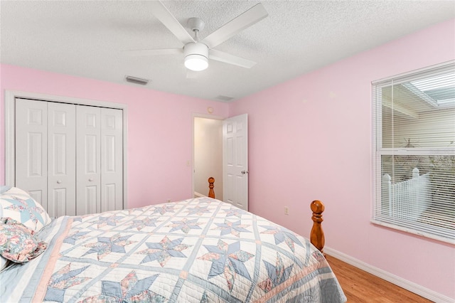 bedroom with a textured ceiling, ceiling fan, light hardwood / wood-style flooring, and a closet