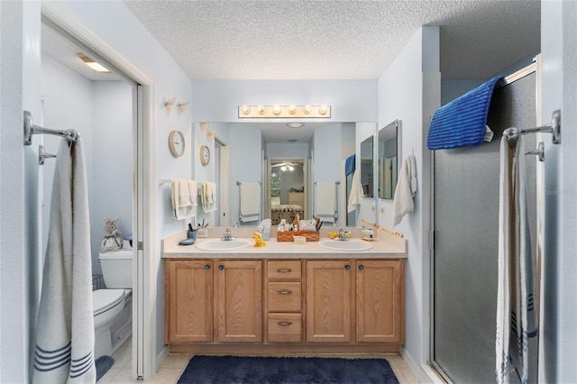 bathroom with vanity, a textured ceiling, toilet, and an enclosed shower