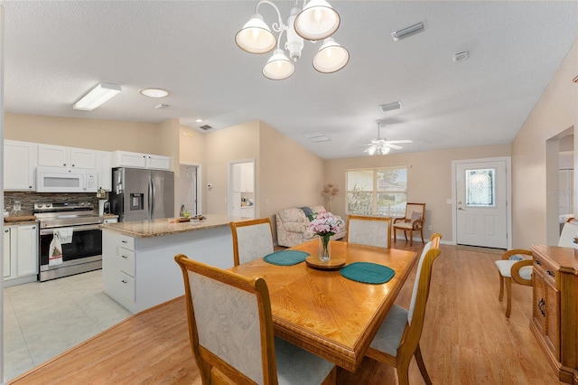 dining room featuring ceiling fan with notable chandelier, light hardwood / wood-style floors, and lofted ceiling