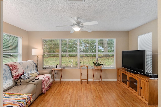 living room featuring ceiling fan, a healthy amount of sunlight, and light wood-type flooring