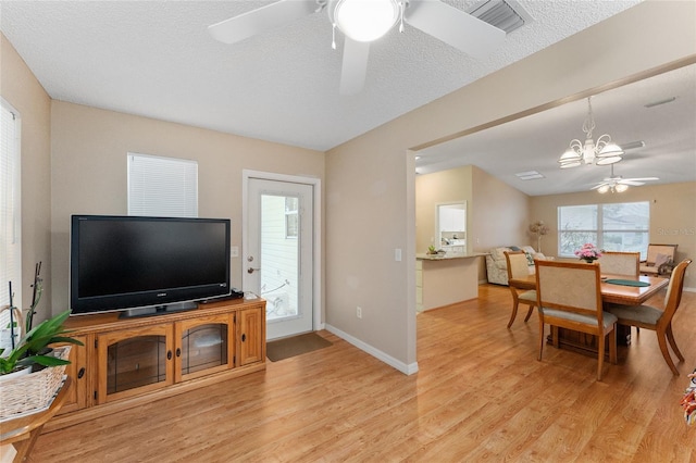 living room with light hardwood / wood-style flooring, ceiling fan with notable chandelier, and a textured ceiling