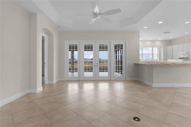 unfurnished room with french doors, light tile patterned floors, a raised ceiling, and ceiling fan