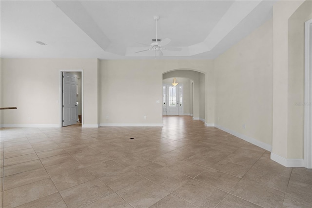 unfurnished room featuring ceiling fan, light tile patterned flooring, and a raised ceiling