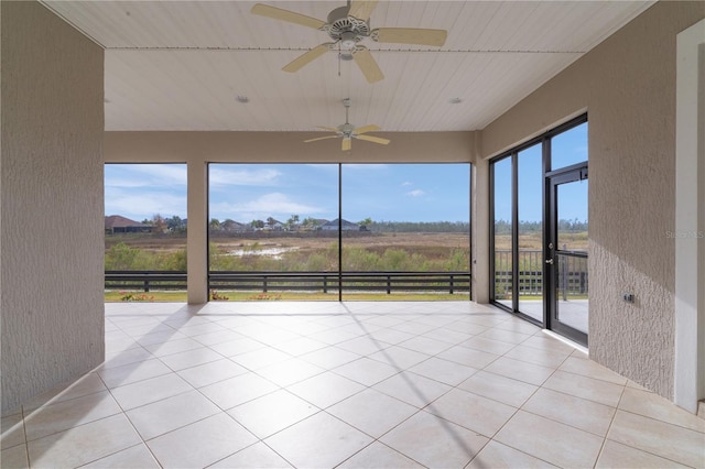 unfurnished sunroom with ceiling fan and a rural view