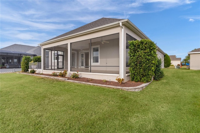 back of house featuring a sunroom, ceiling fan, and a lawn