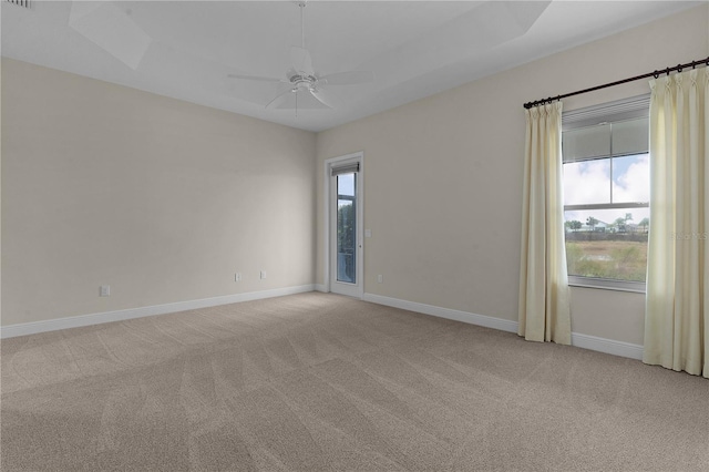 carpeted spare room with a tray ceiling and ceiling fan