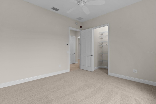 unfurnished bedroom featuring ceiling fan, a closet, light carpet, and a spacious closet