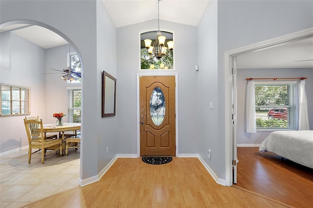 foyer entrance featuring ceiling fan with notable chandelier, light hardwood / wood-style floors, and high vaulted ceiling