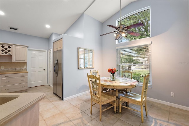 tiled dining area with ceiling fan and high vaulted ceiling