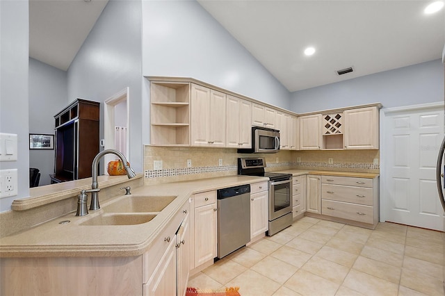 kitchen featuring kitchen peninsula, tasteful backsplash, stainless steel appliances, sink, and high vaulted ceiling