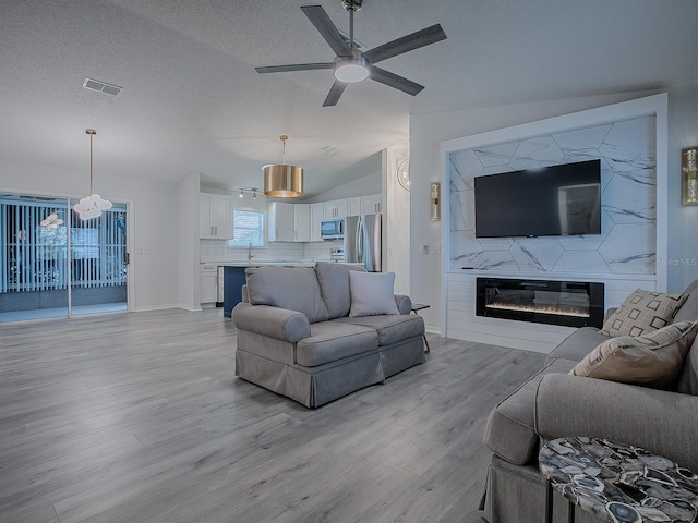 living room with plenty of natural light, light wood-type flooring, and vaulted ceiling