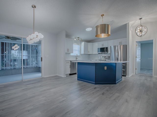 kitchen featuring white cabinets, pendant lighting, stainless steel appliances, and a kitchen island