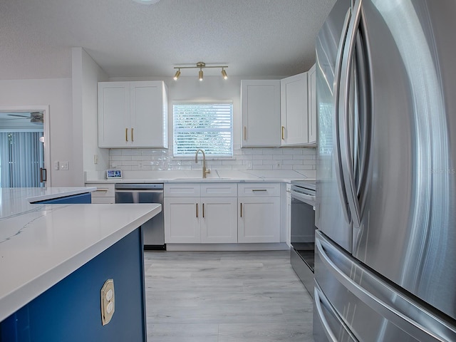 kitchen with sink, white cabinets, stainless steel appliances, and light hardwood / wood-style flooring