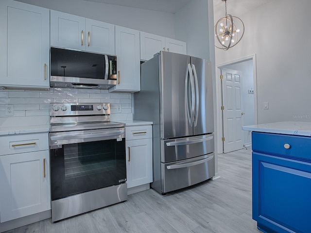 kitchen featuring decorative backsplash, light stone counters, stainless steel appliances, light hardwood / wood-style flooring, and white cabinetry