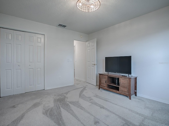 bedroom with light carpet, a closet, and a textured ceiling