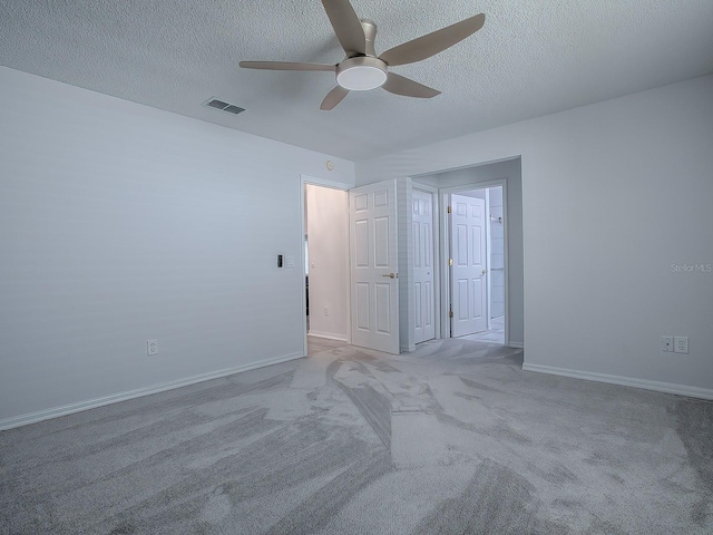 empty room featuring a textured ceiling, light colored carpet, and ceiling fan