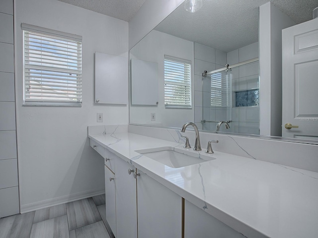 bathroom featuring vanity, a shower with shower door, and a textured ceiling