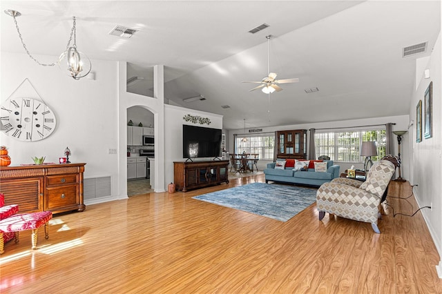 living room with ceiling fan with notable chandelier, light hardwood / wood-style floors, and vaulted ceiling