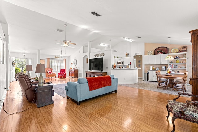 living room featuring ceiling fan, lofted ceiling, and light wood-type flooring