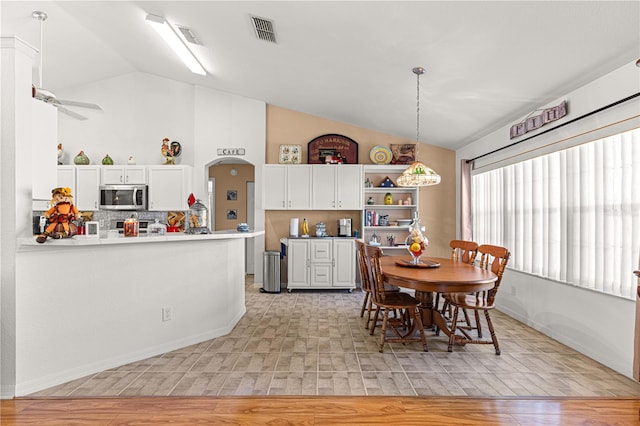 dining room with ceiling fan, light wood-type flooring, and vaulted ceiling