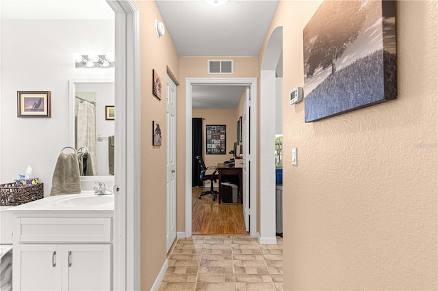 corridor with sink and a textured ceiling