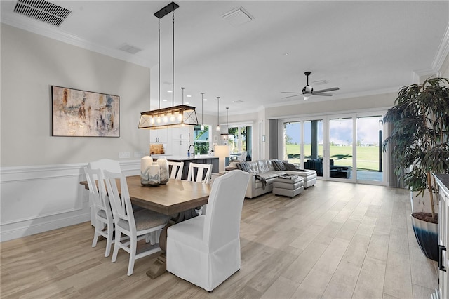 dining space featuring ceiling fan, light hardwood / wood-style flooring, and ornamental molding