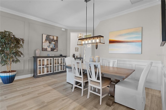 dining room with light wood-type flooring, an inviting chandelier, and crown molding