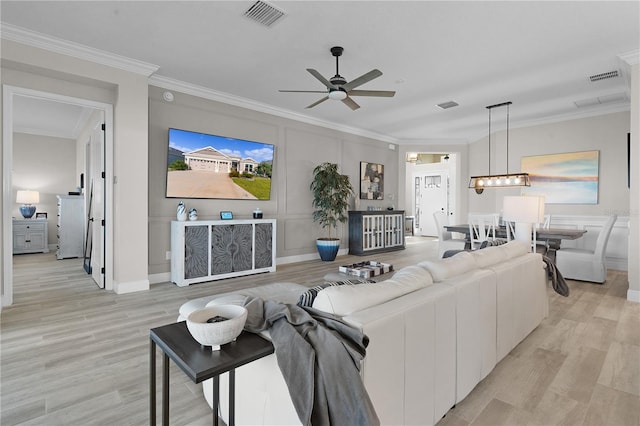 living room featuring ceiling fan, ornamental molding, and light wood-type flooring