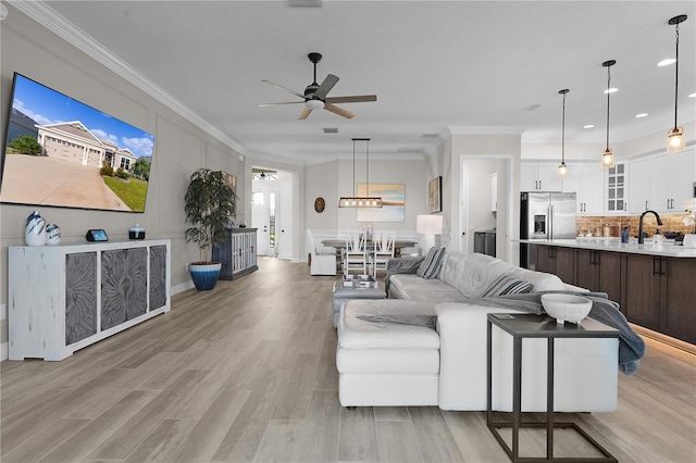 living room featuring ceiling fan, light hardwood / wood-style flooring, sink, and ornamental molding