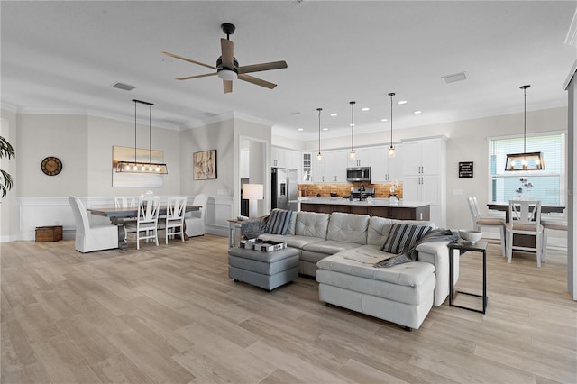 living room featuring light wood-type flooring, ceiling fan, and ornamental molding