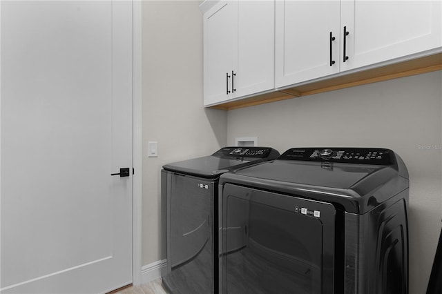 clothes washing area with cabinets, separate washer and dryer, and light wood-type flooring