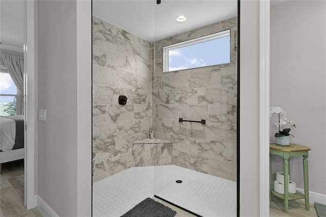 bathroom with tiled shower, hardwood / wood-style floors, and plenty of natural light