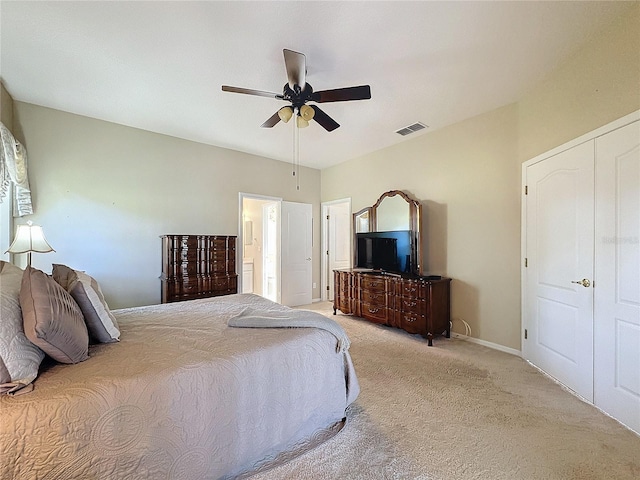 bedroom featuring ceiling fan, light colored carpet, and ensuite bathroom