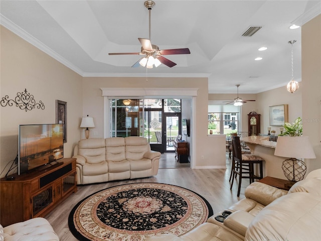 living area with a ceiling fan, baseboards, visible vents, light wood-style flooring, and ornamental molding