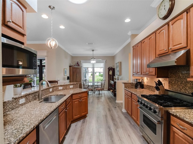 kitchen featuring light wood finished floors, crown molding, under cabinet range hood, light stone counters, and stainless steel appliances