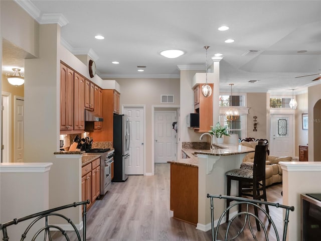 kitchen with under cabinet range hood, stainless steel appliances, a kitchen breakfast bar, and visible vents